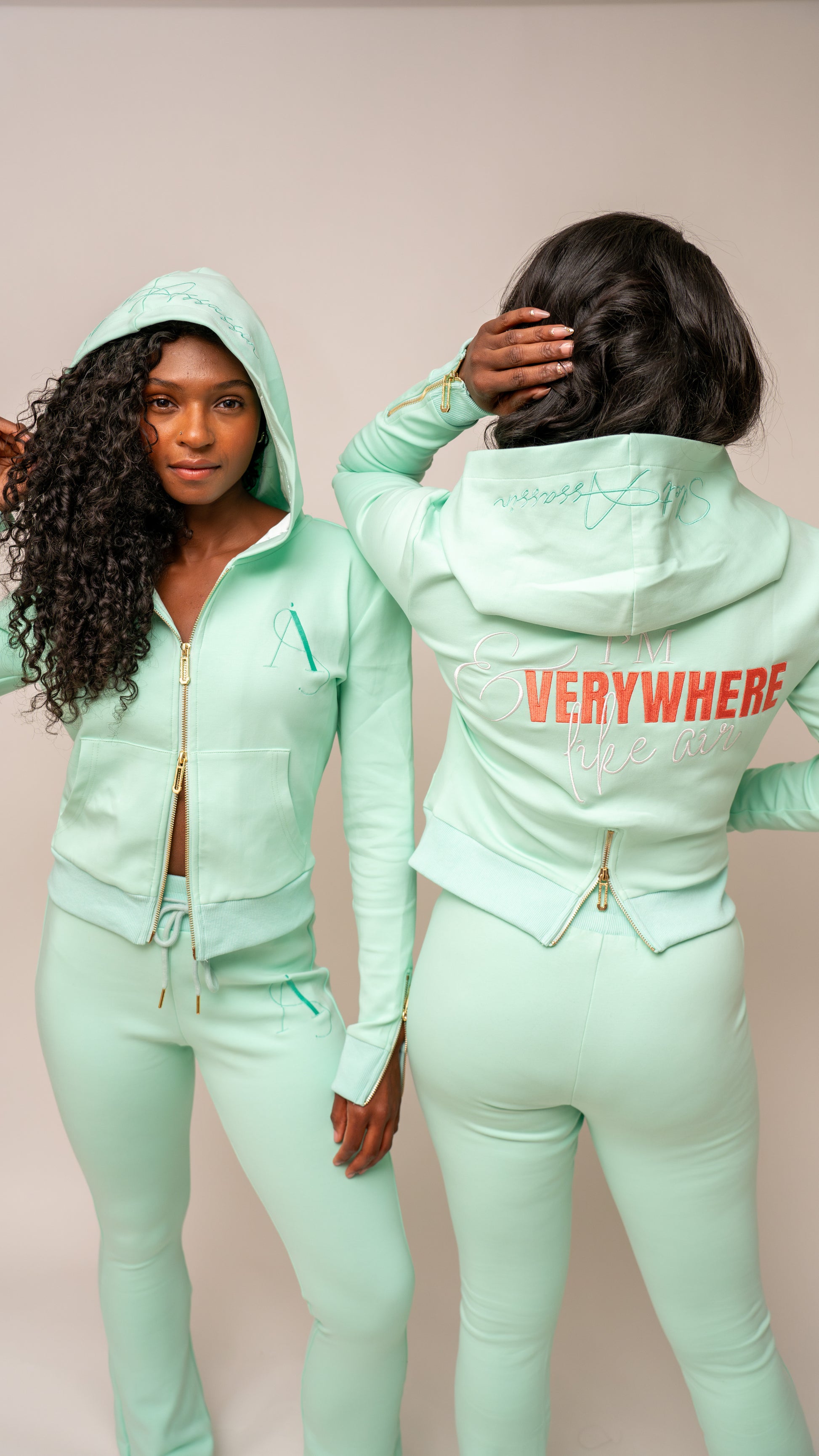 Person wearing a mint green tracksuit with 'VERYWHERE' text on the back against a beige background